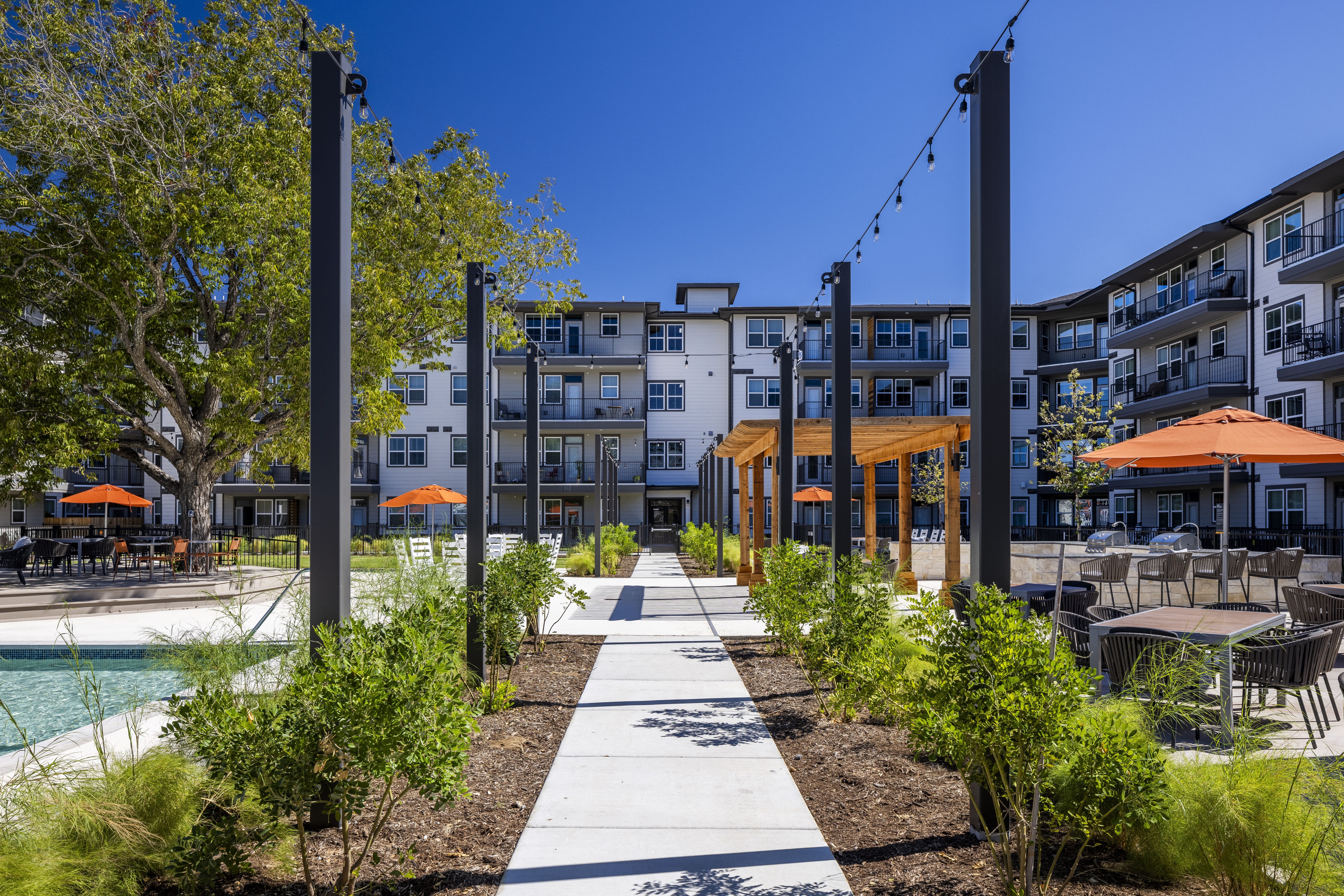a sidewalk in a courtyard lined with greenery at a senior apartment community